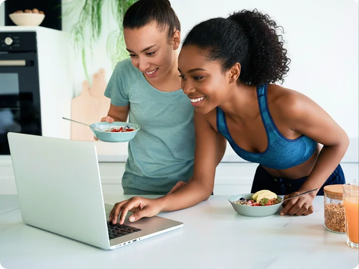 Two women reviewing healthy meal ideas on a laptop